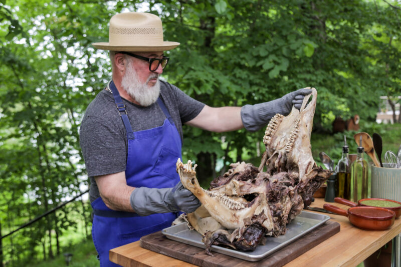 Andrew Zimmern pulls meat from the cow head